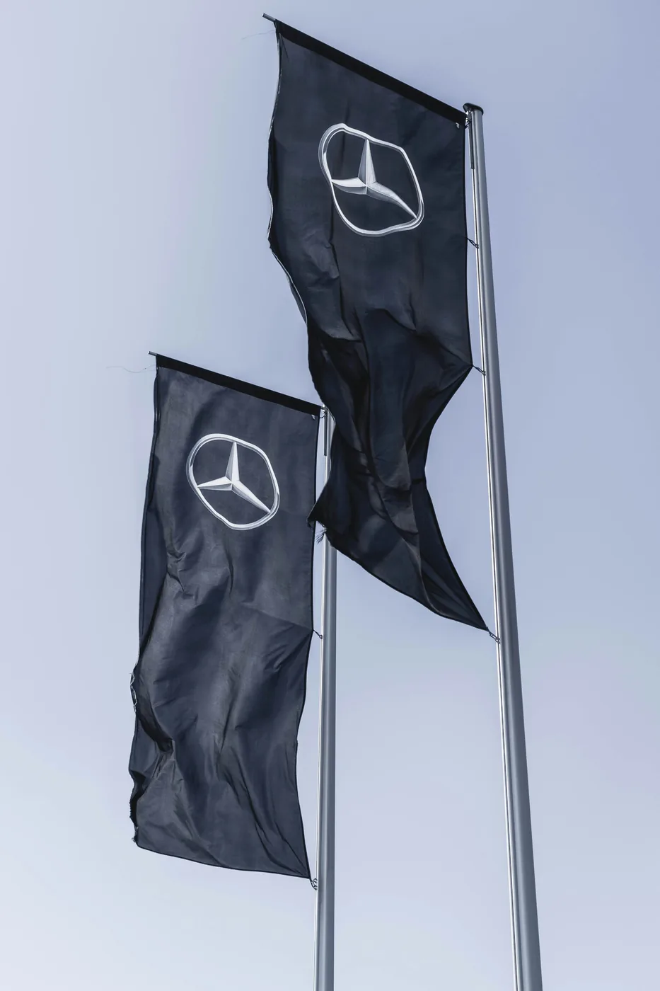 Banderas corporativas Mercedes-Benz sobre mástiles, como referencia de identidad visual en exteriores.