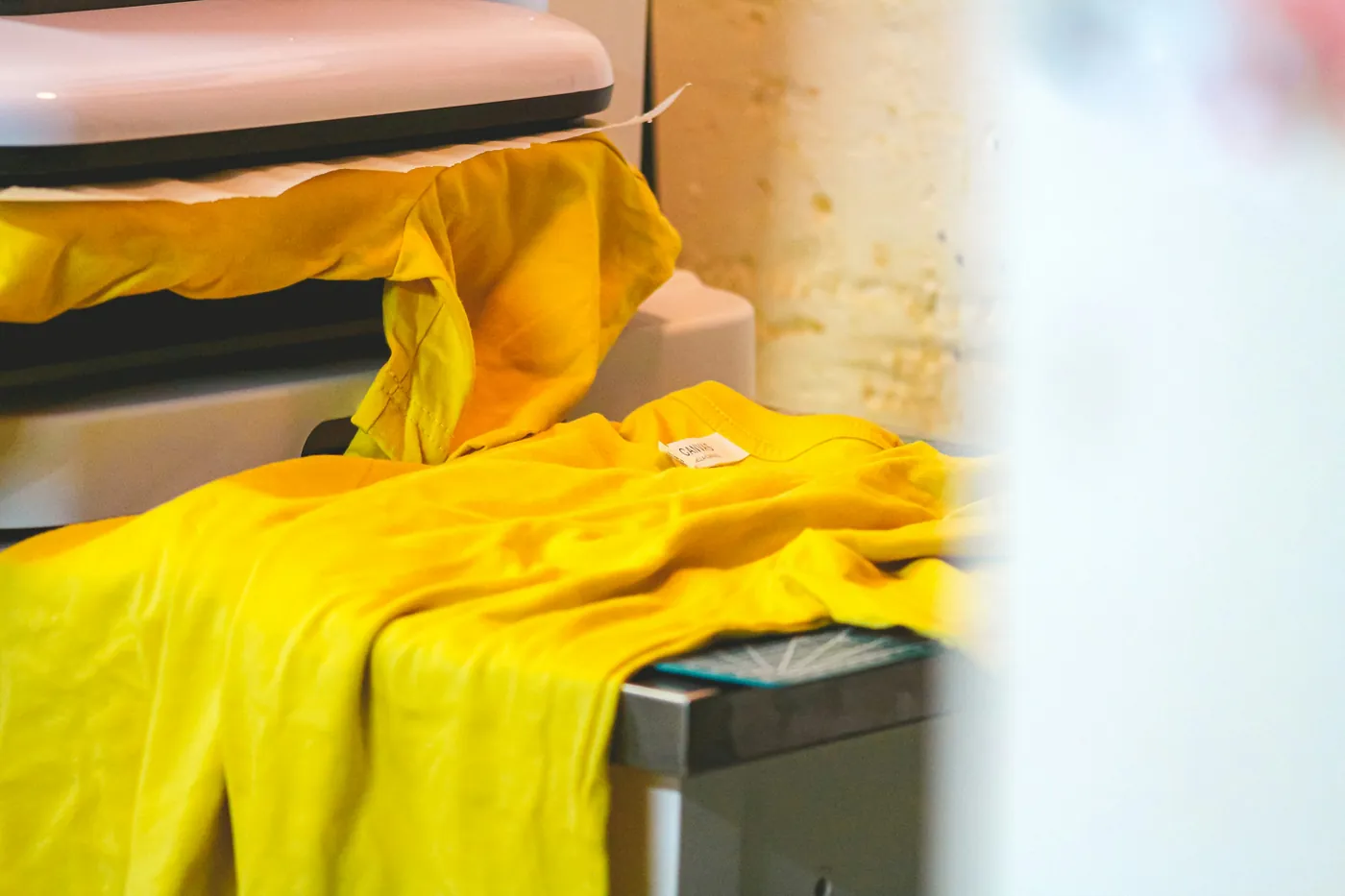 Prensa térmica y playeras durante un proceso de estampado por transferencia.